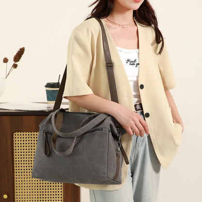 Large grey retro-style canvas shoulder bag with a horizontal square shape and multiple internal pockets.
