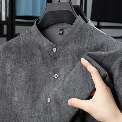 Man wearing a loose-fit grey linen blend short-sleeve shirt with a stand collar.