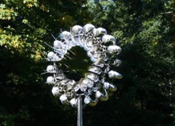 Elegant stainless steel outdoor windmill spinner with dual-layered blades rotating in opposite directions, creating a mesmerising display in the garden