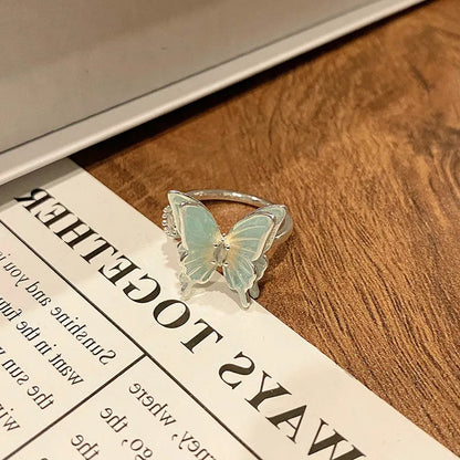 Copper butterfly women's ring with an open loop design on a plain background.