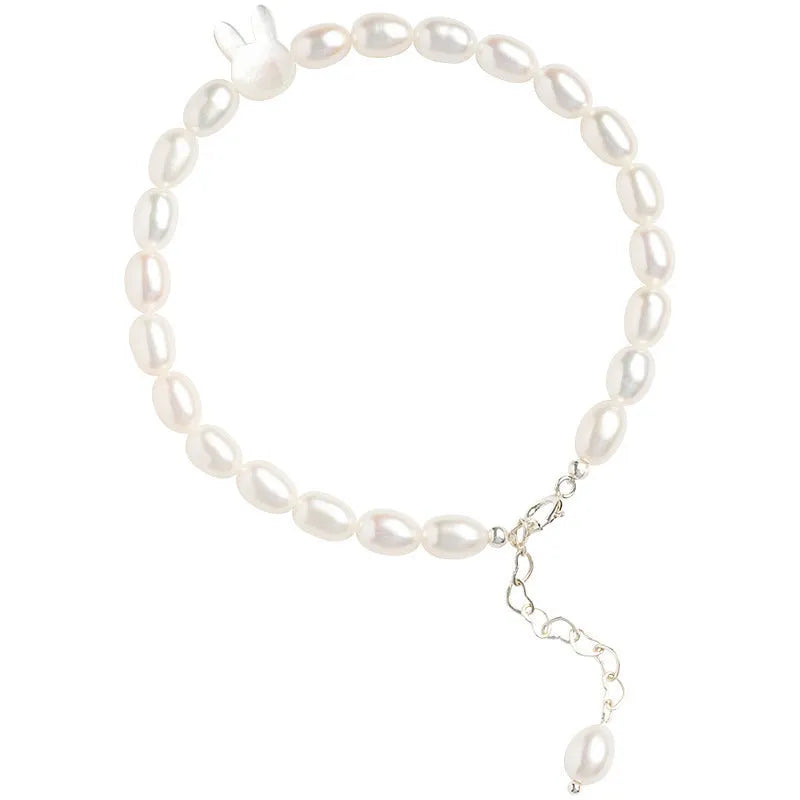 White pearl elastic bracelet with small rice-shaped beads and silver rabbit charm on wrist