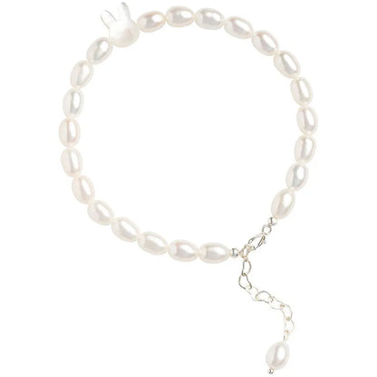 White pearl elastic bracelet with small rice-shaped beads and silver rabbit charm on wrist