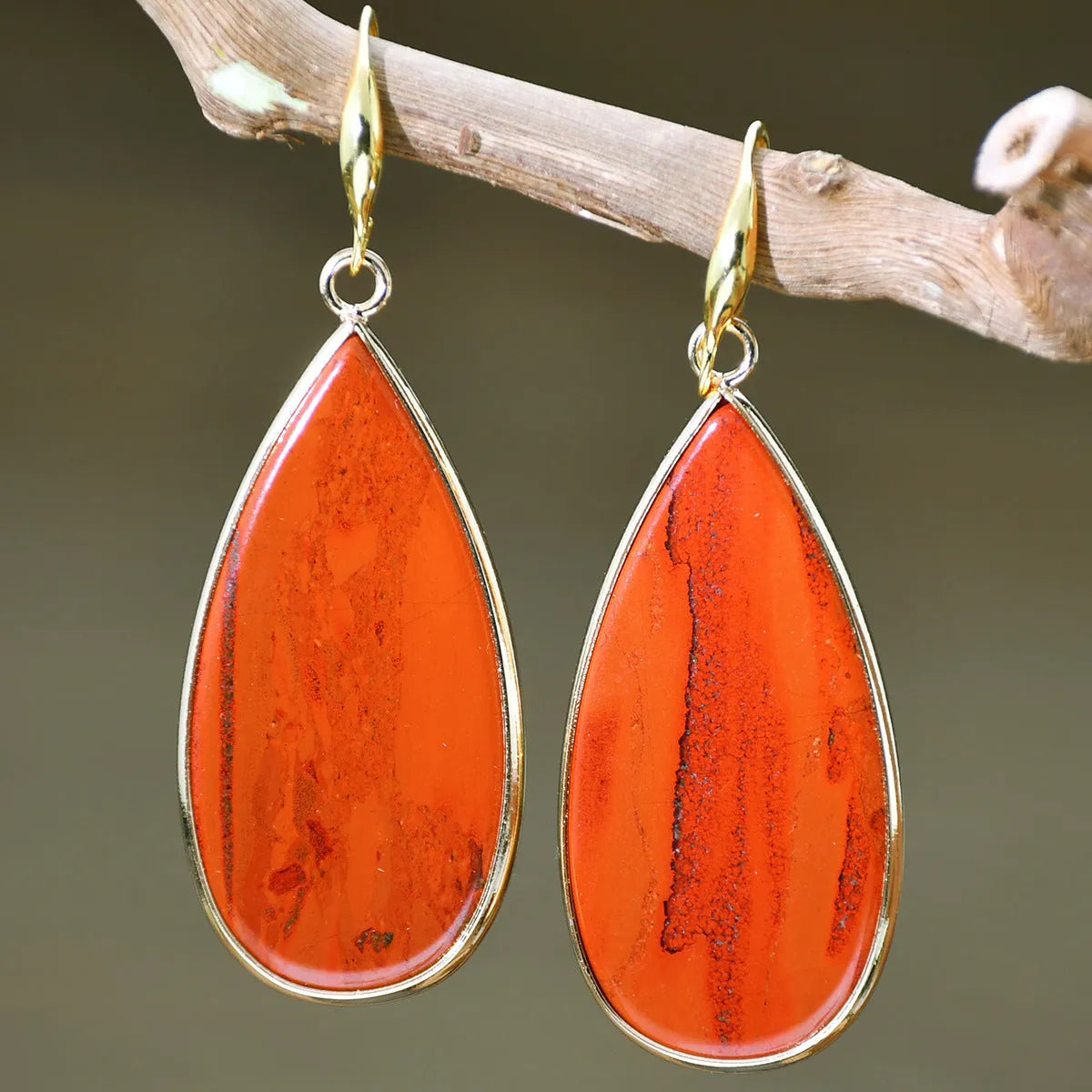 Handmade vintage long water drop earrings with tigereye stone and sterling silver hooks on a textured background.
