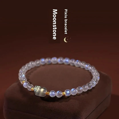 Close-up of a women's moonstone bracelet with an animal or Zodiac motif on a blue background.
