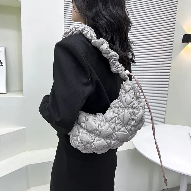 Women's light grey nylon underarm messenger bag with adjustable long strap, shown worn crossbody.