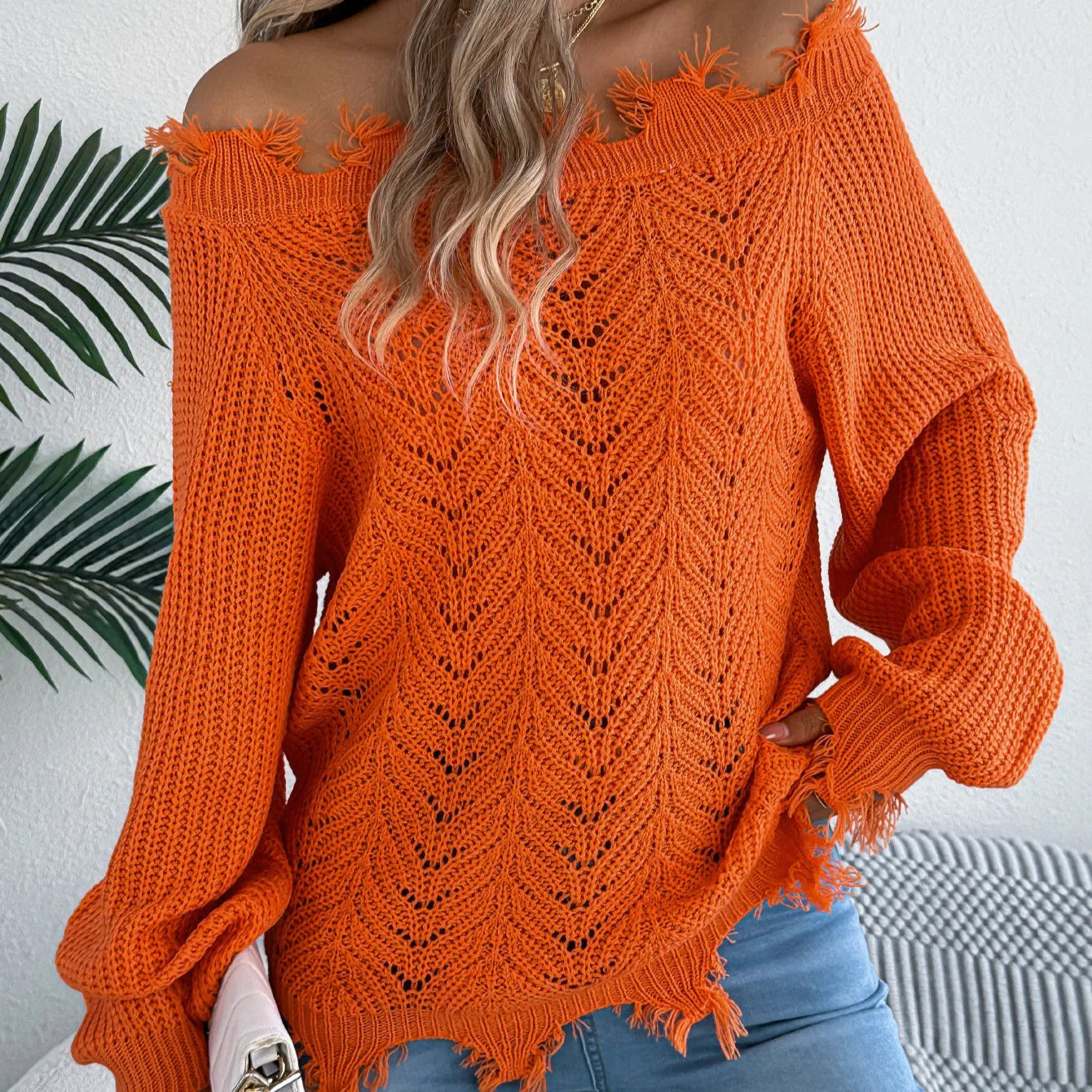 Women's black off-the-shoulder pullover sweater with hollow-out long sleeves on a hanger.