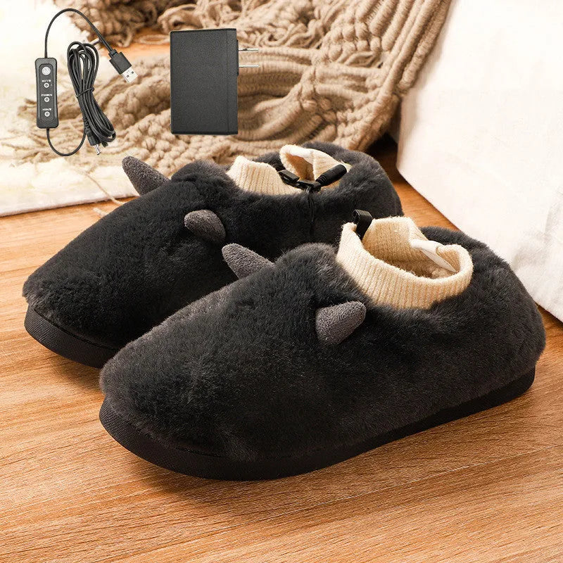 USB heating slippers in black plugged into a laptop, showing the cable and soft velvet upper.