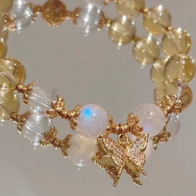 Close-up of a citrine-coloured crystal bracelet with diamond-shaped beads and a butterfly charm.