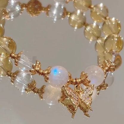 Close-up of a citrine-coloured crystal bracelet with diamond-shaped beads and a butterfly charm.