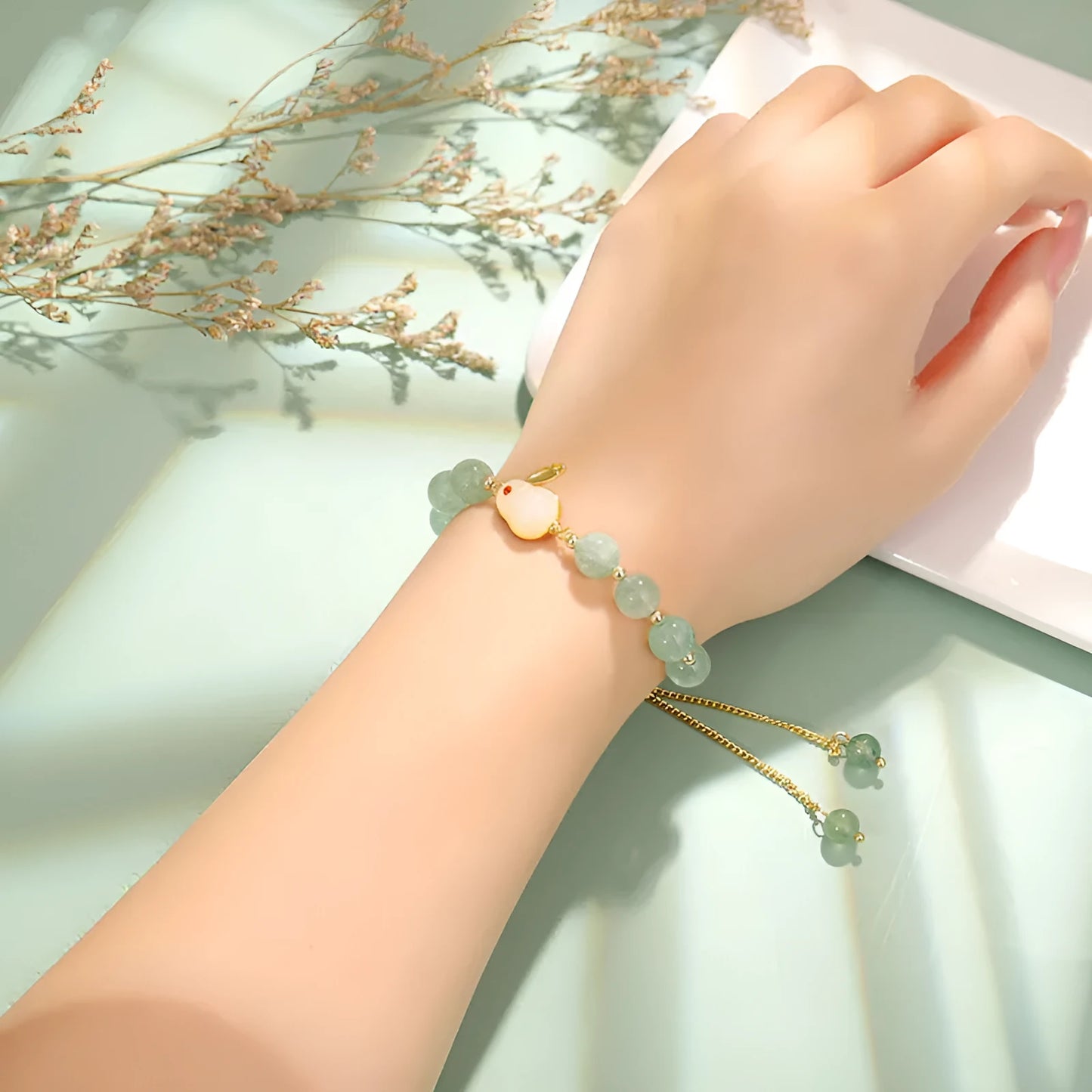Adjustable rabbit charm bracelet with natural stone beads and gold plated details on a wrist.