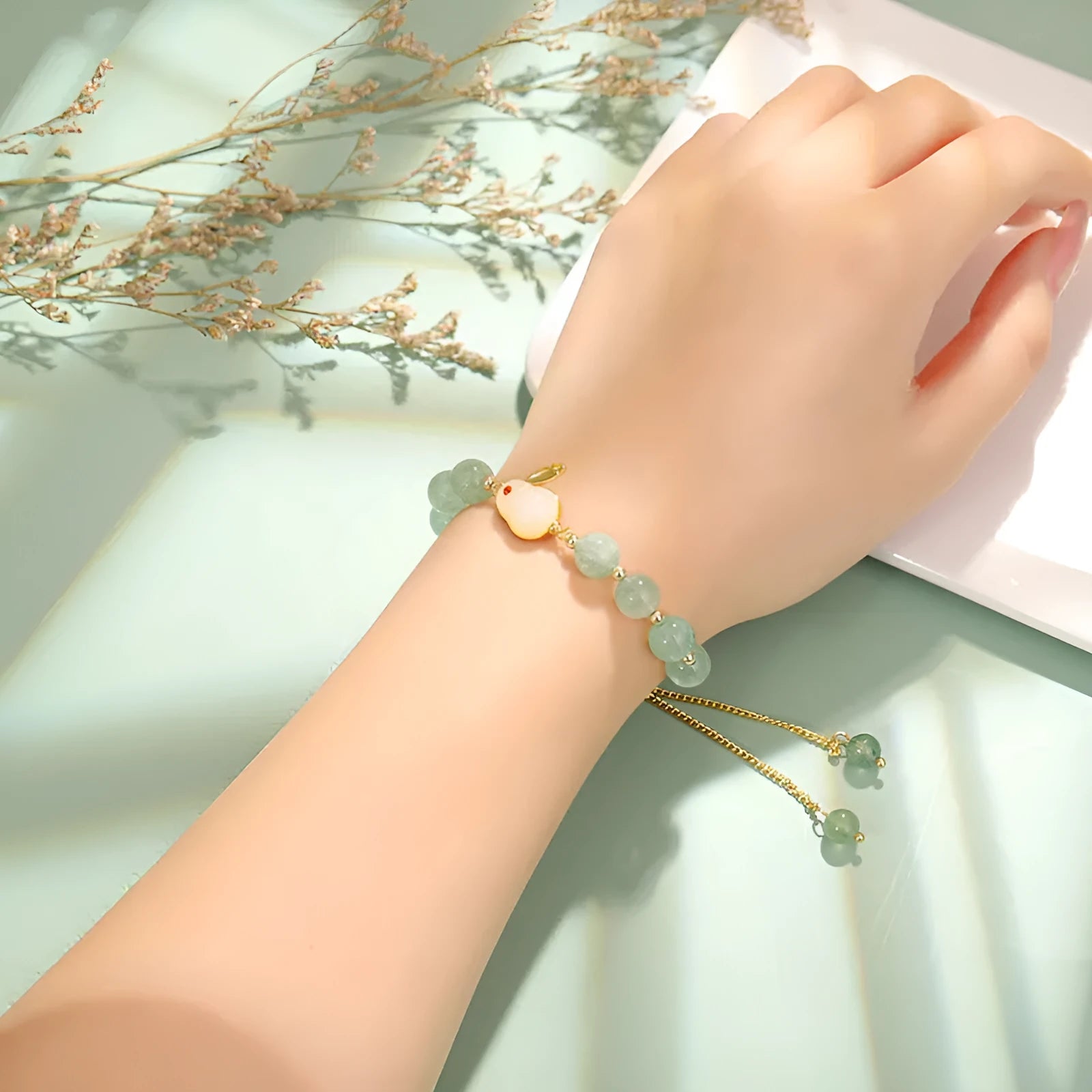 Adjustable rabbit charm bracelet with natural stone beads and gold plated details on a wrist.