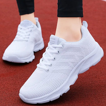 Women's white mesh leisure shoes with lace-up front and low heel on a neutral background.