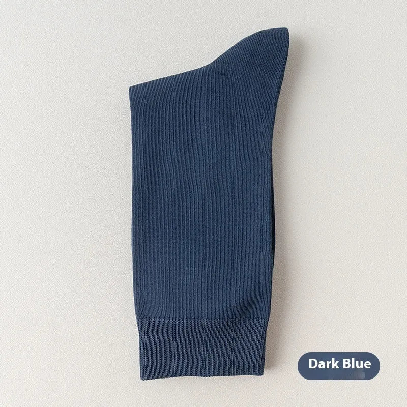 Pair of solid-colour men's mid-calf socks made from combed cotton on a wooden background