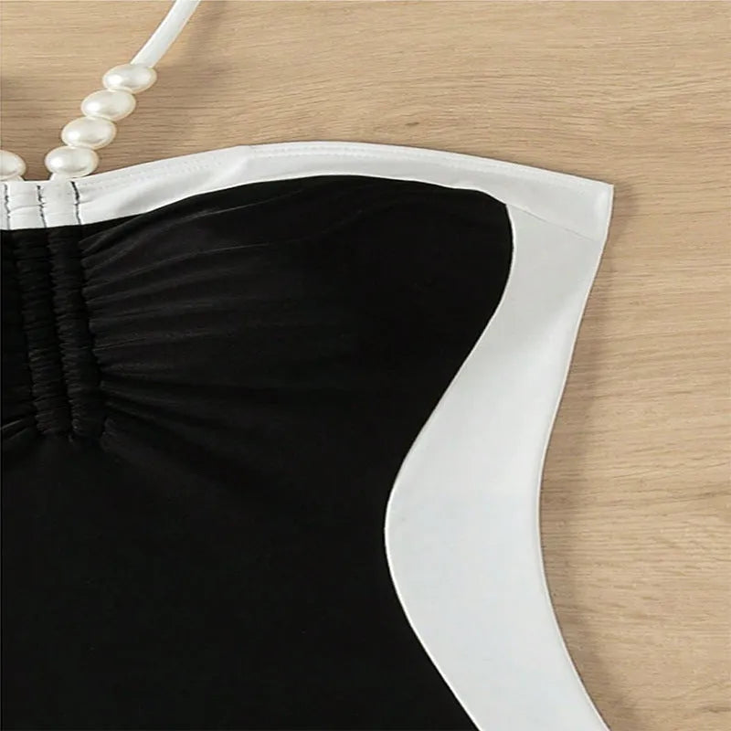 Women's black and white one-piece swimsuit with pearl spaghetti straps and a slimming silhouette.