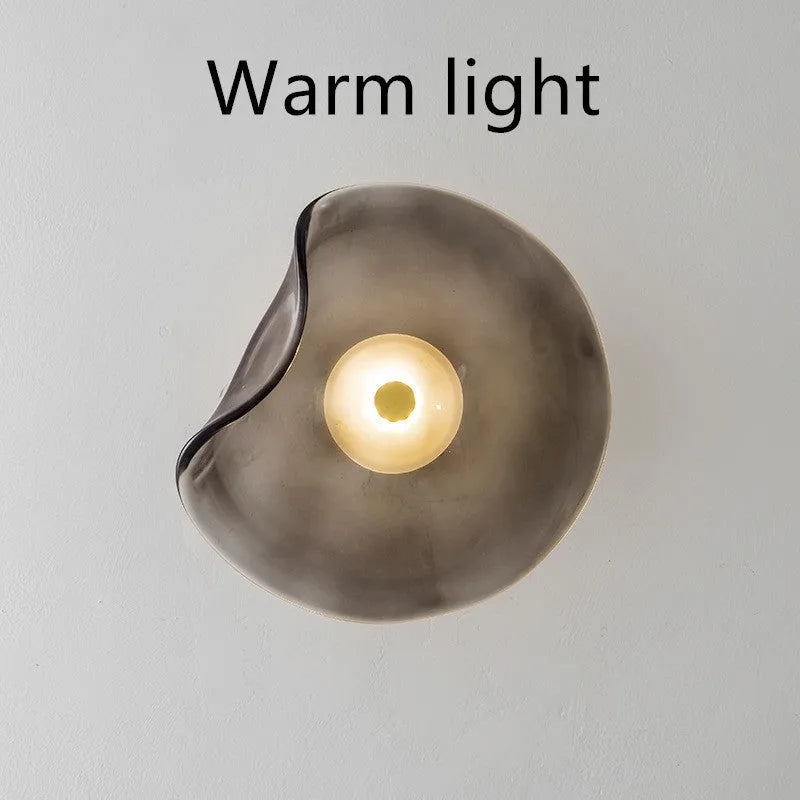 Round glass wall lamp mounted beside bed in cognac colour with 220V operation for bedside lighting