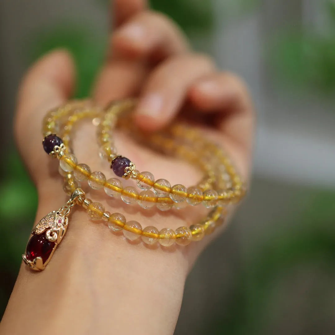 Natural gold rutilated quartz bracelet with Chinese style three circles and hanging chopsticks design.