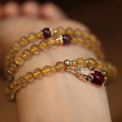 Natural gold rutilated quartz bracelet with Chinese style three circles and hanging chopsticks design.