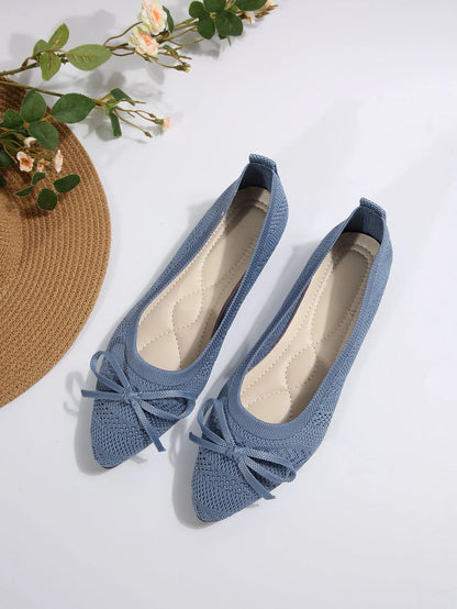 Women's blue knitted loafer flat shoes with a pointed toe and decorative bow detail on the front.