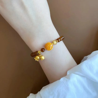 Caramel-coloured women's bracelet with beeswax Lily, music note, and blessing charms in New Chinese style.