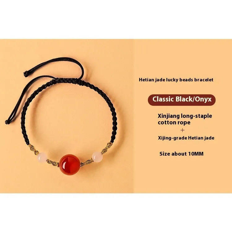 Hand-woven red rope bracelet with Hetian jade lucky beads on a wrist.