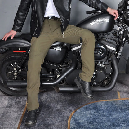 Motorcycle rider wearing green waterproof trousers with removable protective armour on knees and hips.