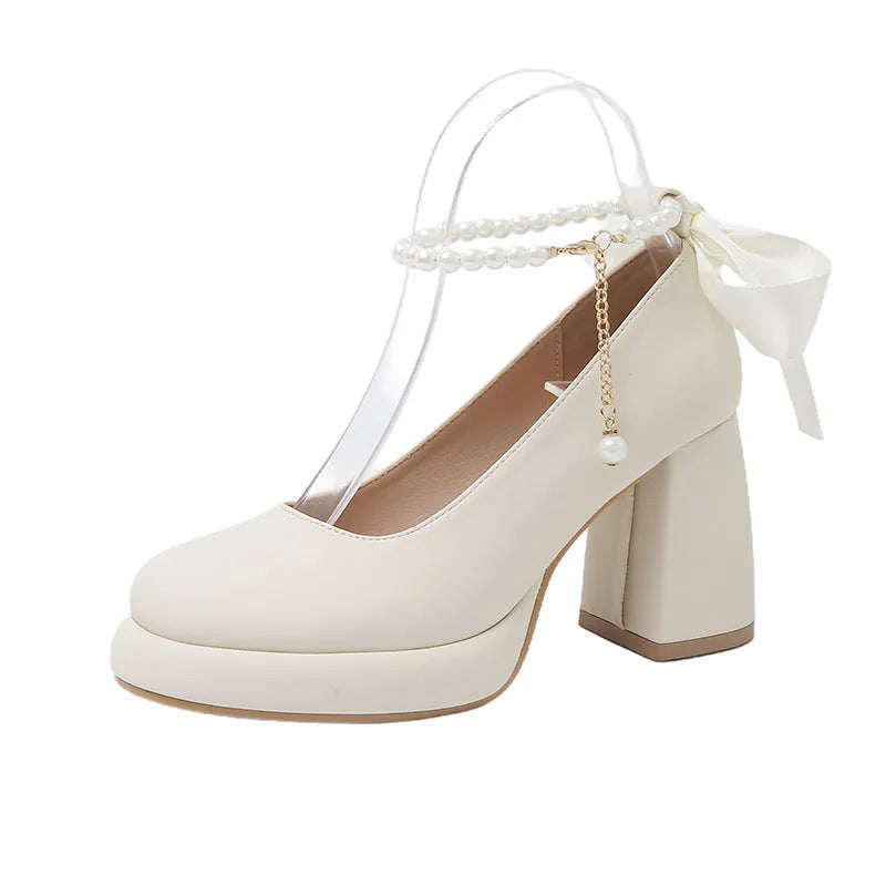 Women's beige preppy style Mary Jane shoes with chunky heel, ankle strap buckle, and pearl detail.