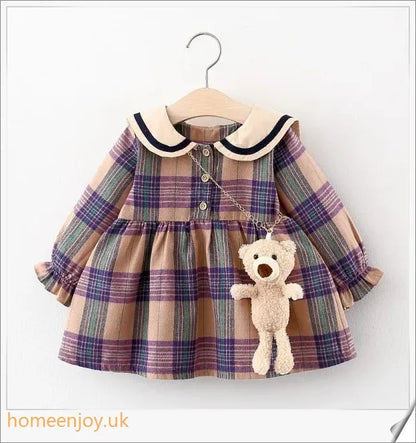 Baby girl wearing a long-sleeve dress with a grid pattern in purple and khaki colours
