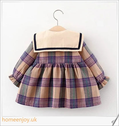 Baby girl wearing a long-sleeve dress with a grid pattern in purple and khaki colours