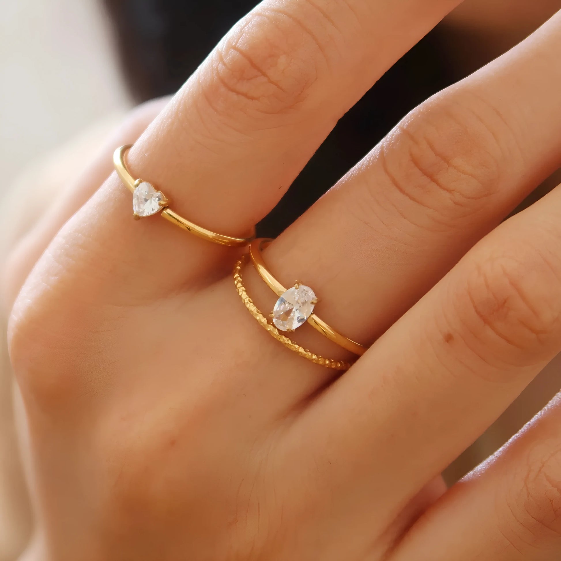A gold-coloured stainless steel ring in a heart shape and an oval shape on a simple band.