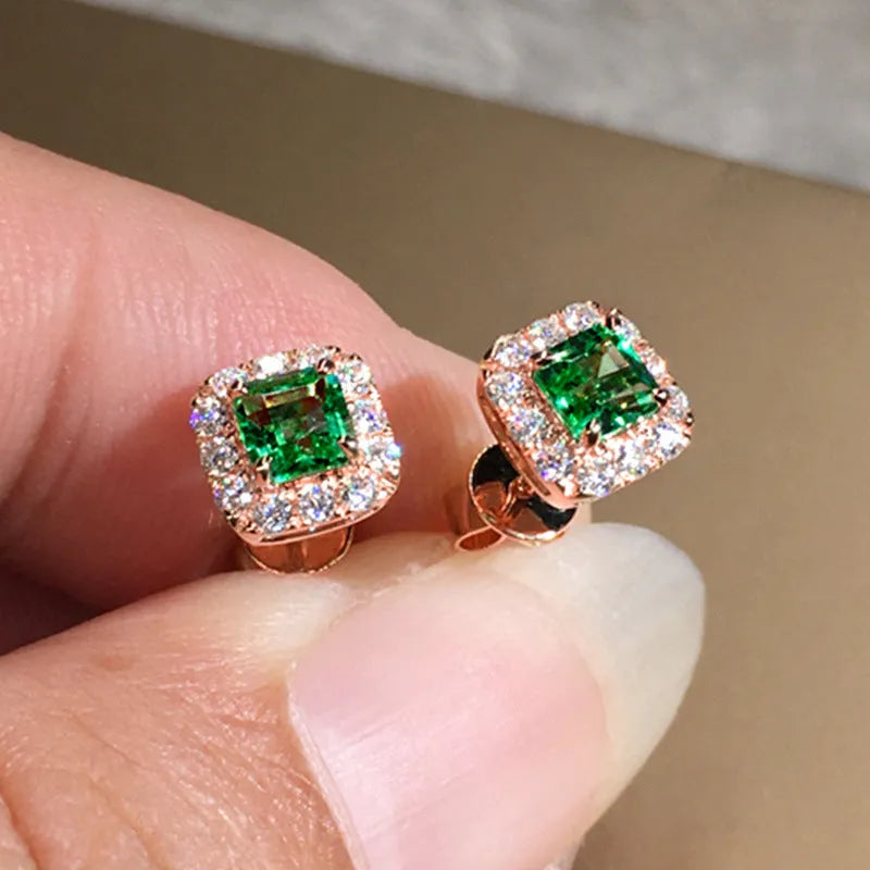 A pair of square cut grandmother green zircon stud earrings with a gold electroplated finish on a white background.