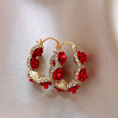 A pair of red rose-shaped clip-on alloy earrings for women on a white background.