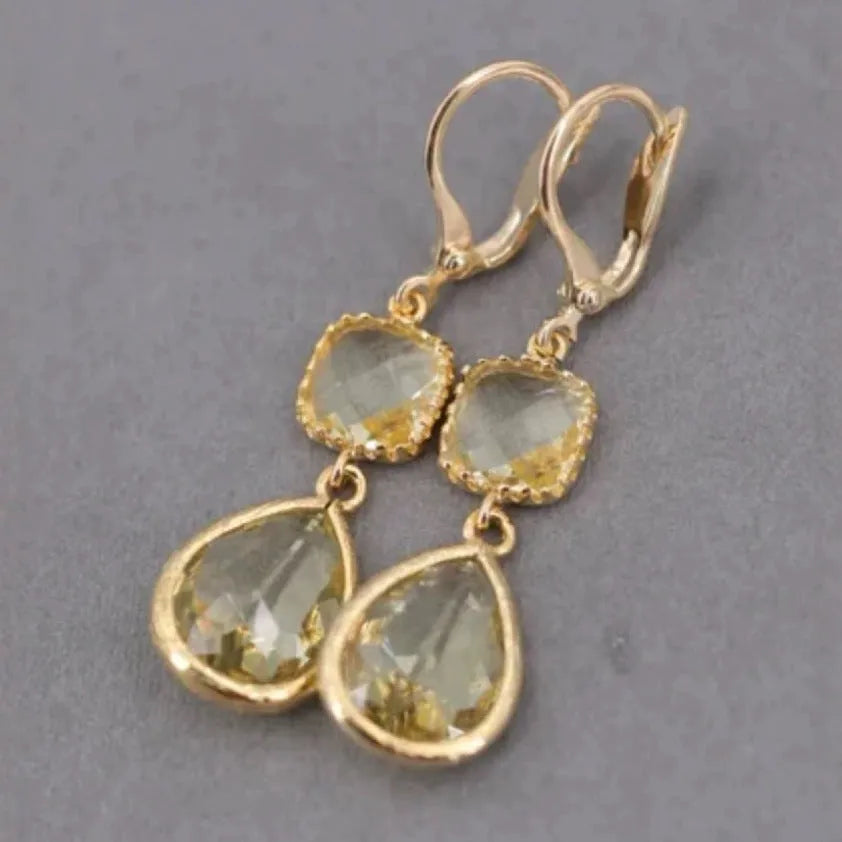 Gold geometric long fringe earrings with crystal water droplets on a white background.