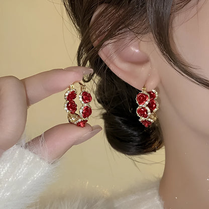 A pair of red rose-shaped clip-on alloy earrings for women on a white background.