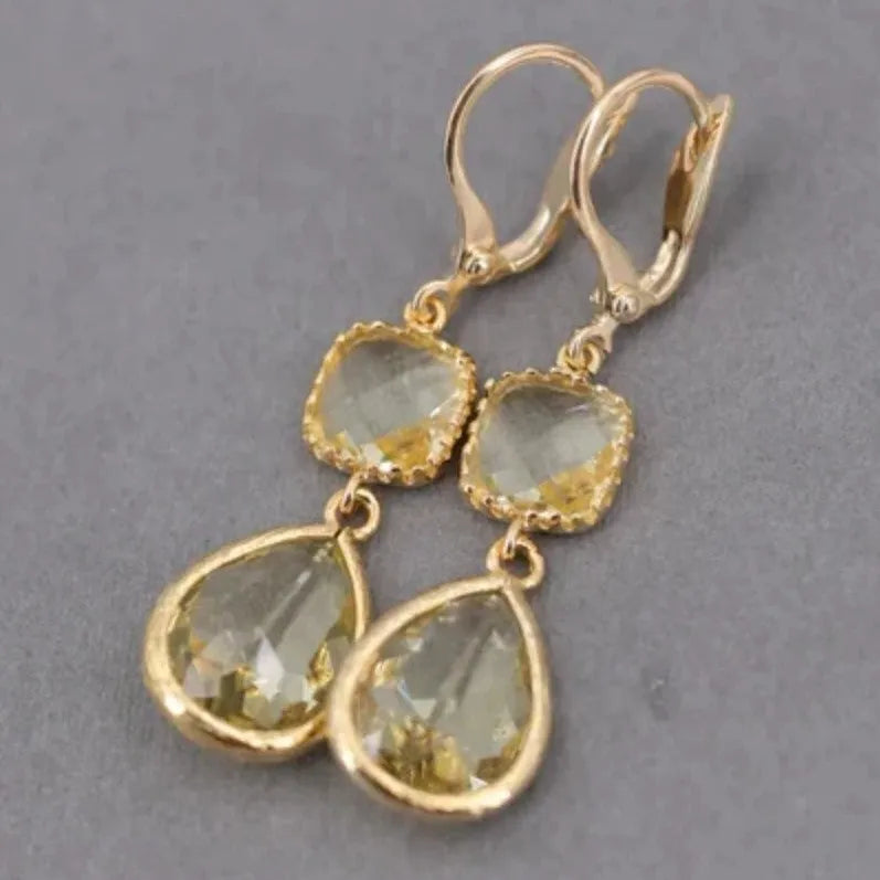 Gold geometric long fringe earrings with crystal water droplets on a white background.