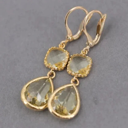 Gold geometric long fringe earrings with crystal water droplets on a white background.
