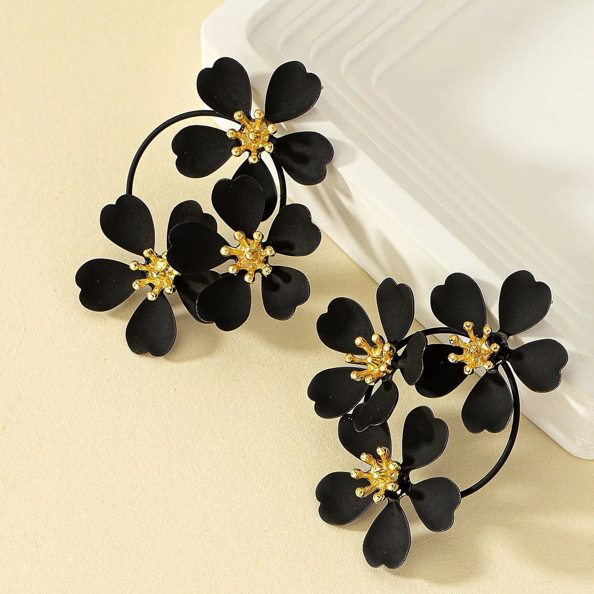 A pair of retro-style flower-shaped earrings for women, shown in black and white colour options.