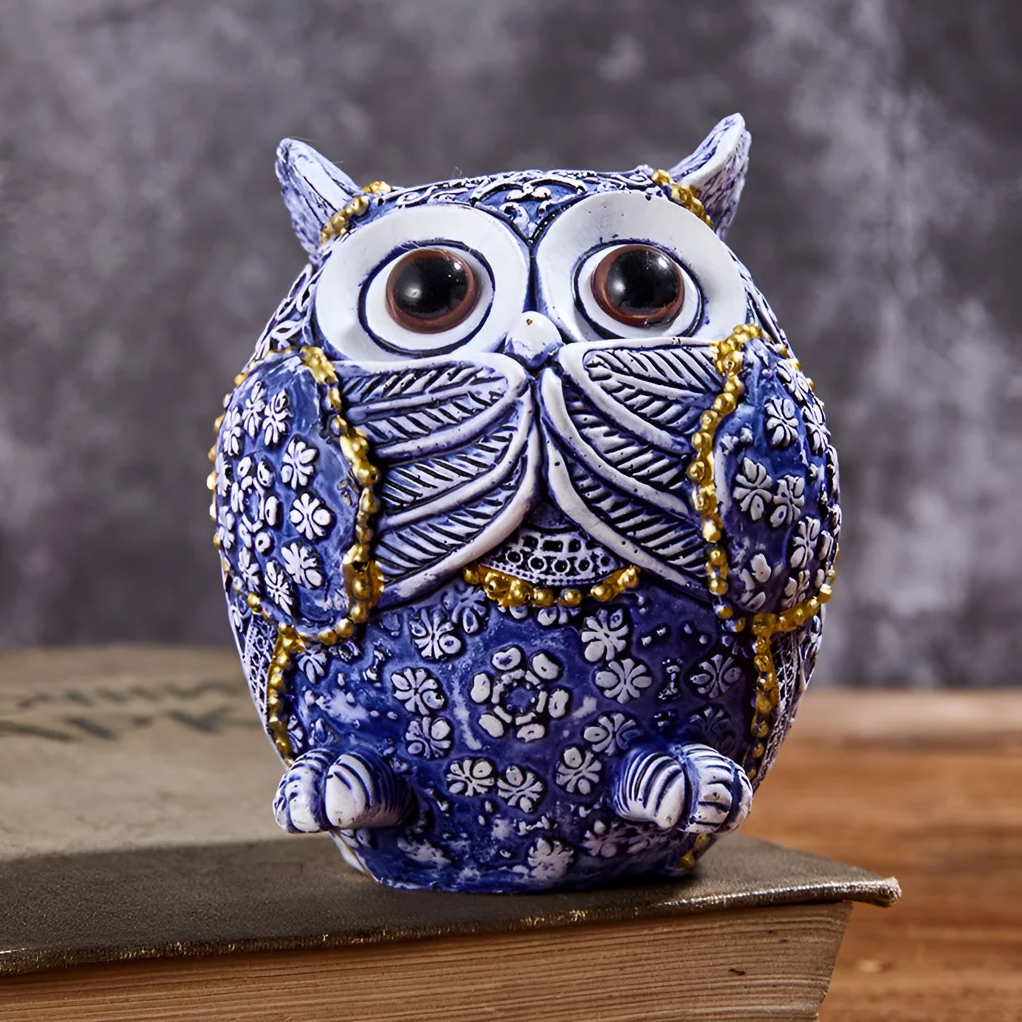 Three blue and white owl resin ornaments with hand-painted pastoral design on wooden surface