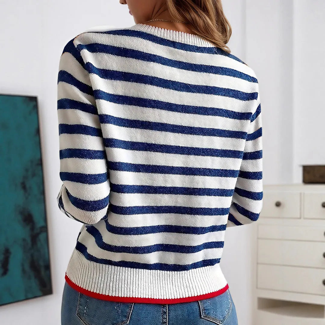 Sapphire blue striped knitted pullover sweater with round neck and long sleeves on a hanger.