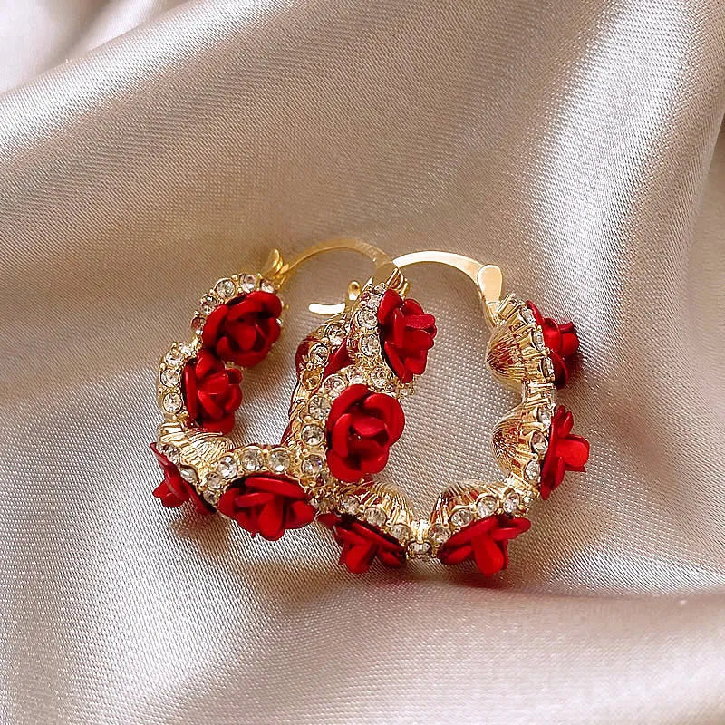 A pair of red rose-shaped clip-on alloy earrings for women on a white background.