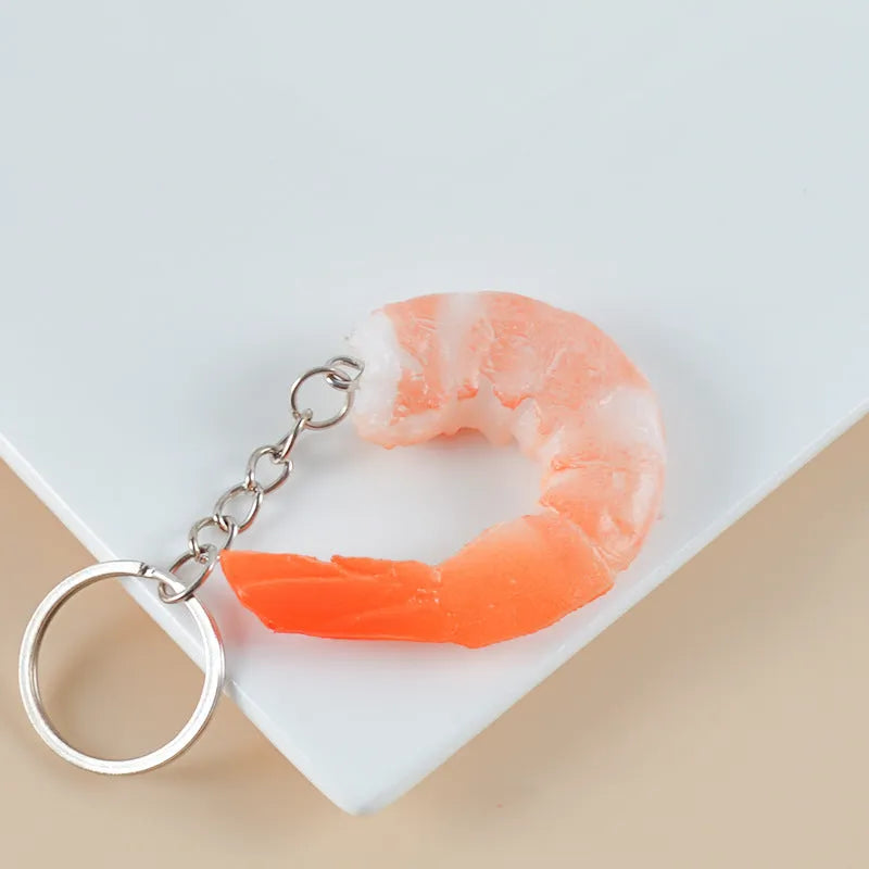 White PVC shrimp-shaped keychain with door buckle on a blue background.