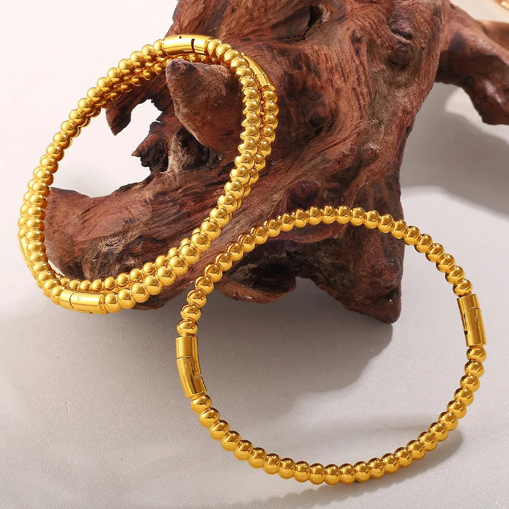 Stainless steel open-end bracelet with a buckle clasp in a choice of gold, silver, or zirconium gold electroplated finishes.
