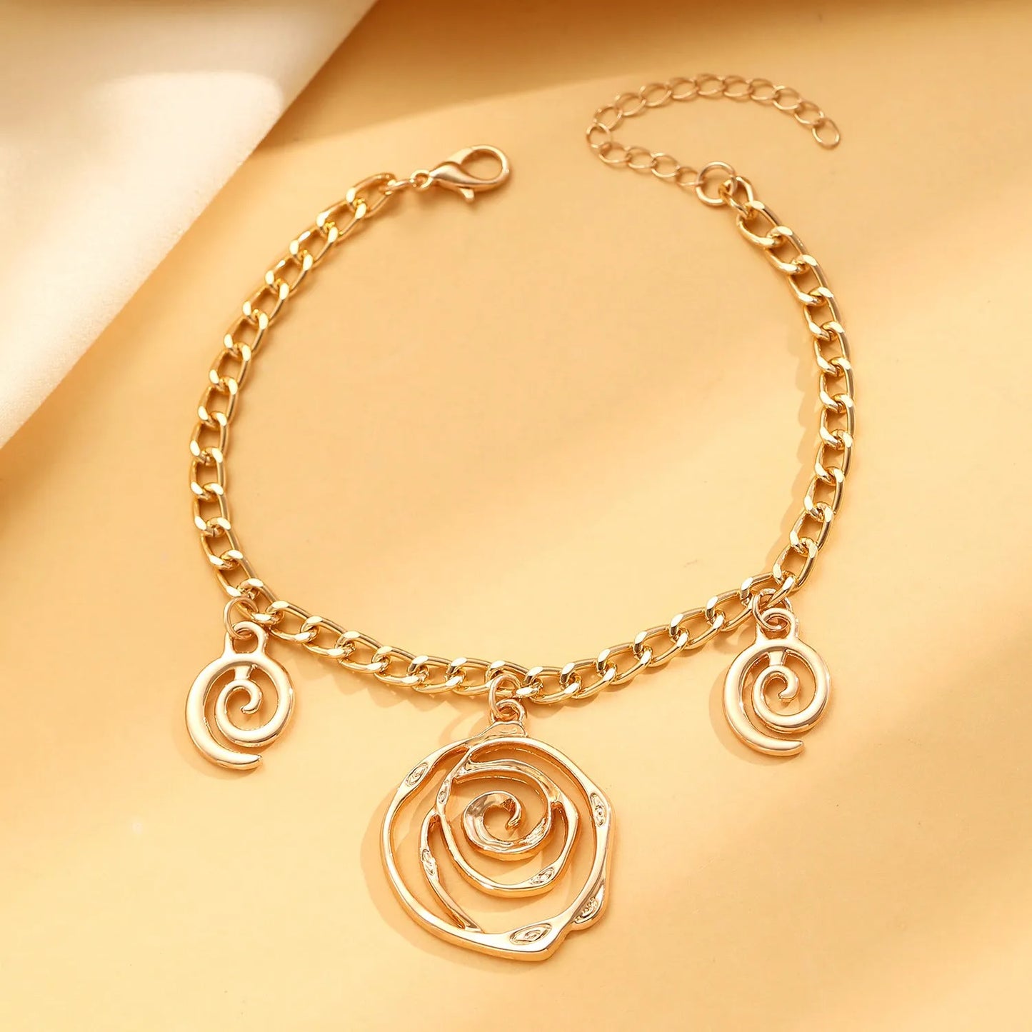 Gold spiral donut alloy jewellery set showing adjustable necklace, matching bracelet, and ear hooks on a plain background.
