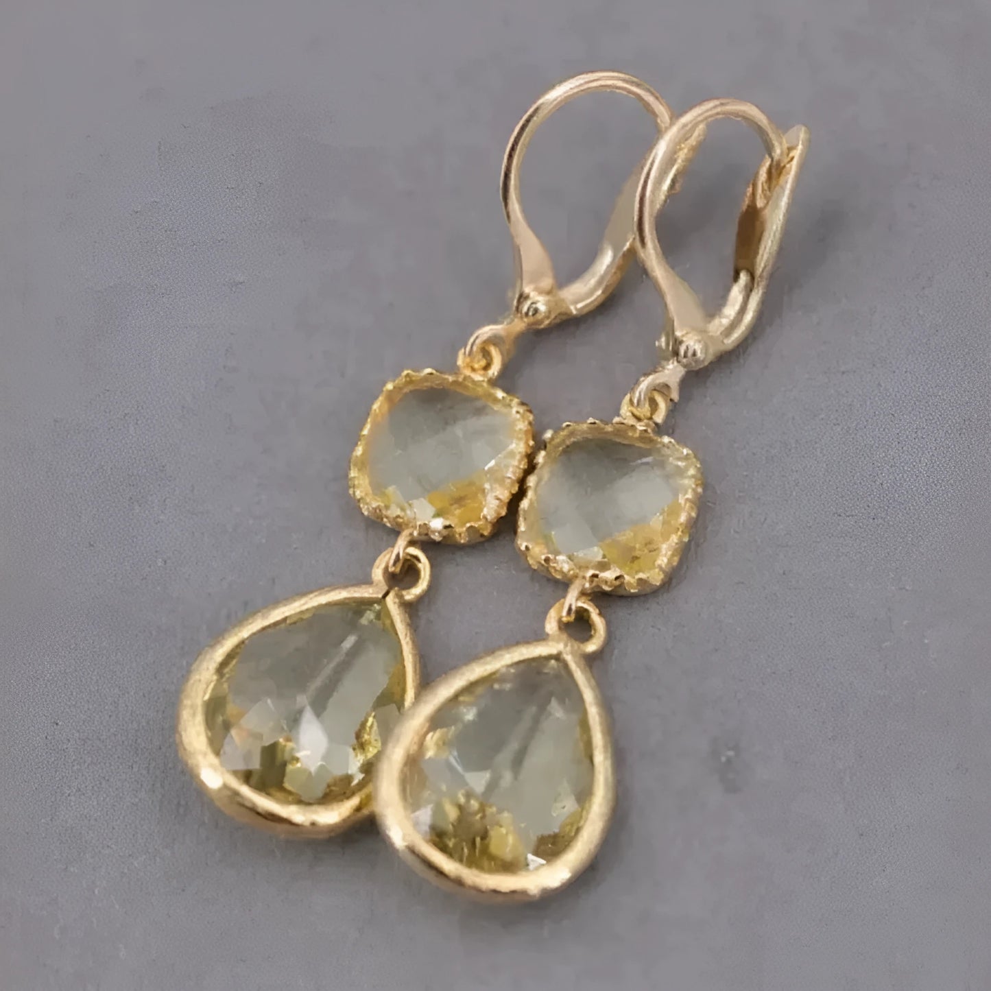 Gold geometric long fringe earrings with crystal water droplets on a white background.