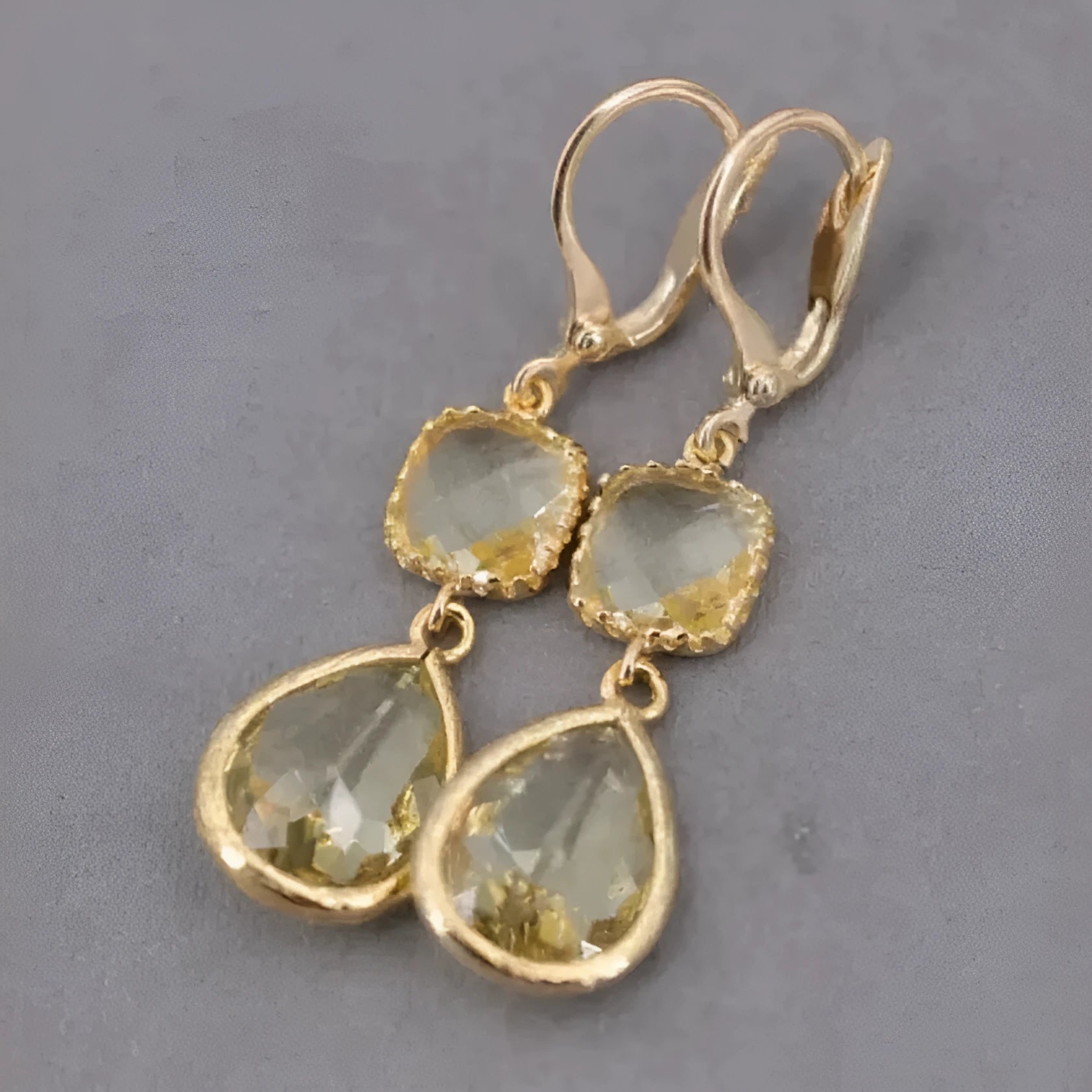 Gold geometric long fringe earrings with crystal water droplets on a white background.