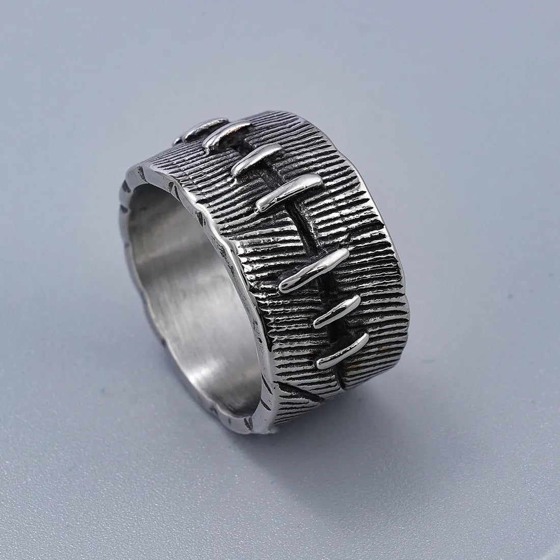Dark geometric titanium steel punk ring showing U-shape and double ring design with stitched texture.