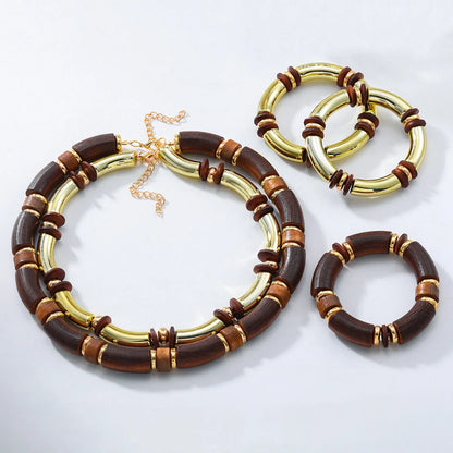 Layered bohemian jewellery set with a large round wooden pendant necklace and matching bracelet on a table.