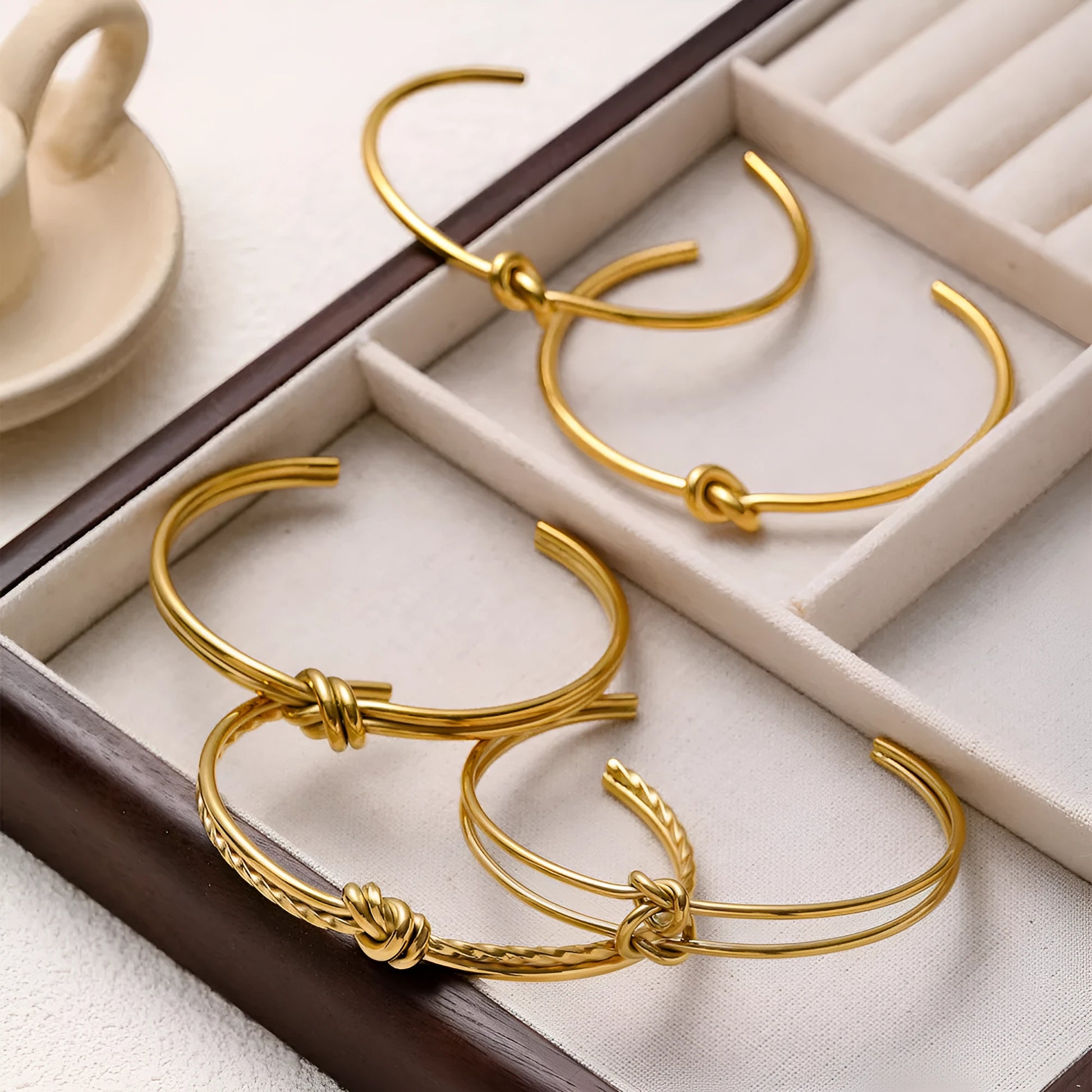 Stainless steel women's bracelet with knotted C-shape open double-layer design in gold or silver.