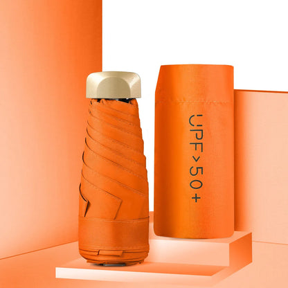 Compact flat-folded sun umbrella in a solid colour, shown next to a hand for scale.