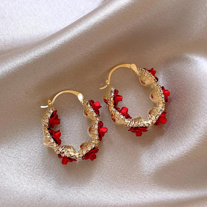 A pair of red rose-shaped clip-on alloy earrings for women on a white background.