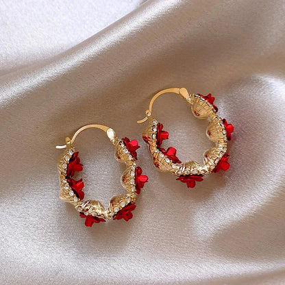 A pair of red rose-shaped clip-on alloy earrings for women on a white background.